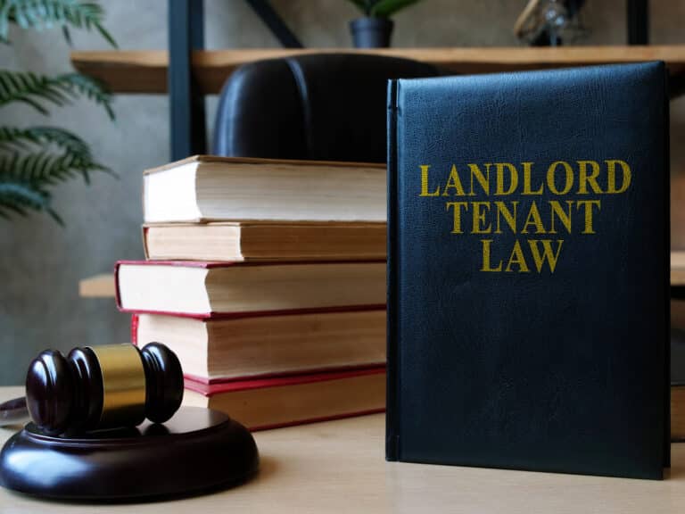 A book titled Landlord Tenant Law stands upright on a desk, surrounded by a stack of books and a judges gavel, essential tools for any Landlord-Tenant lawyer.