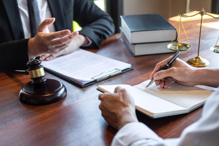 Two people in formal attire sit at a desk with legal documents, discussing asset protection Florida and legal strategies for LLCs Florida.