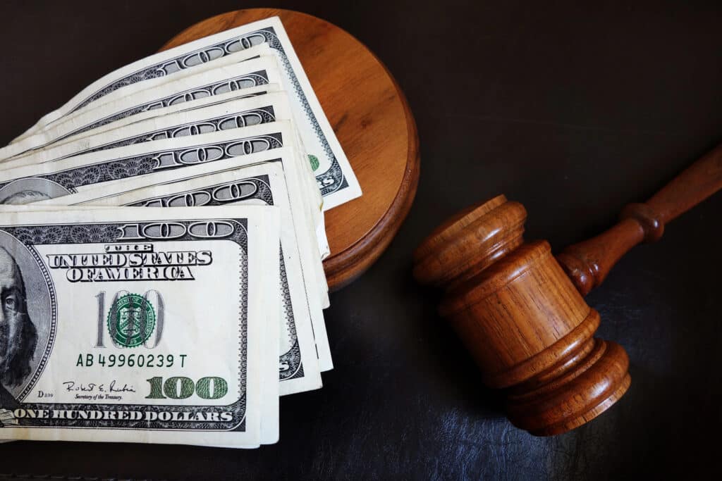 A wooden gavel and a stack of 100-dollar bills rest on a dark surface, representing Florida civil litigation and key financial decisions.